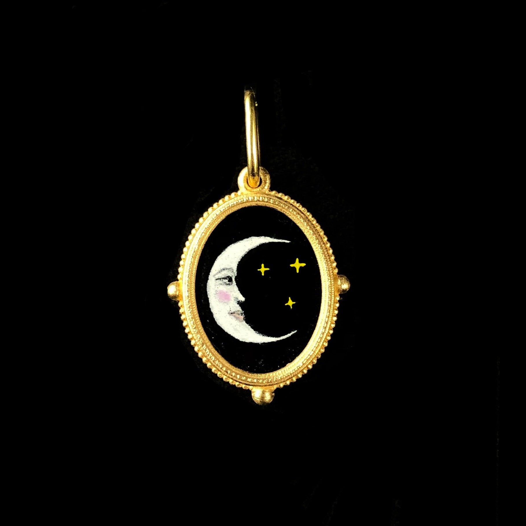 Oval charm with image of crescent moon floating on black 