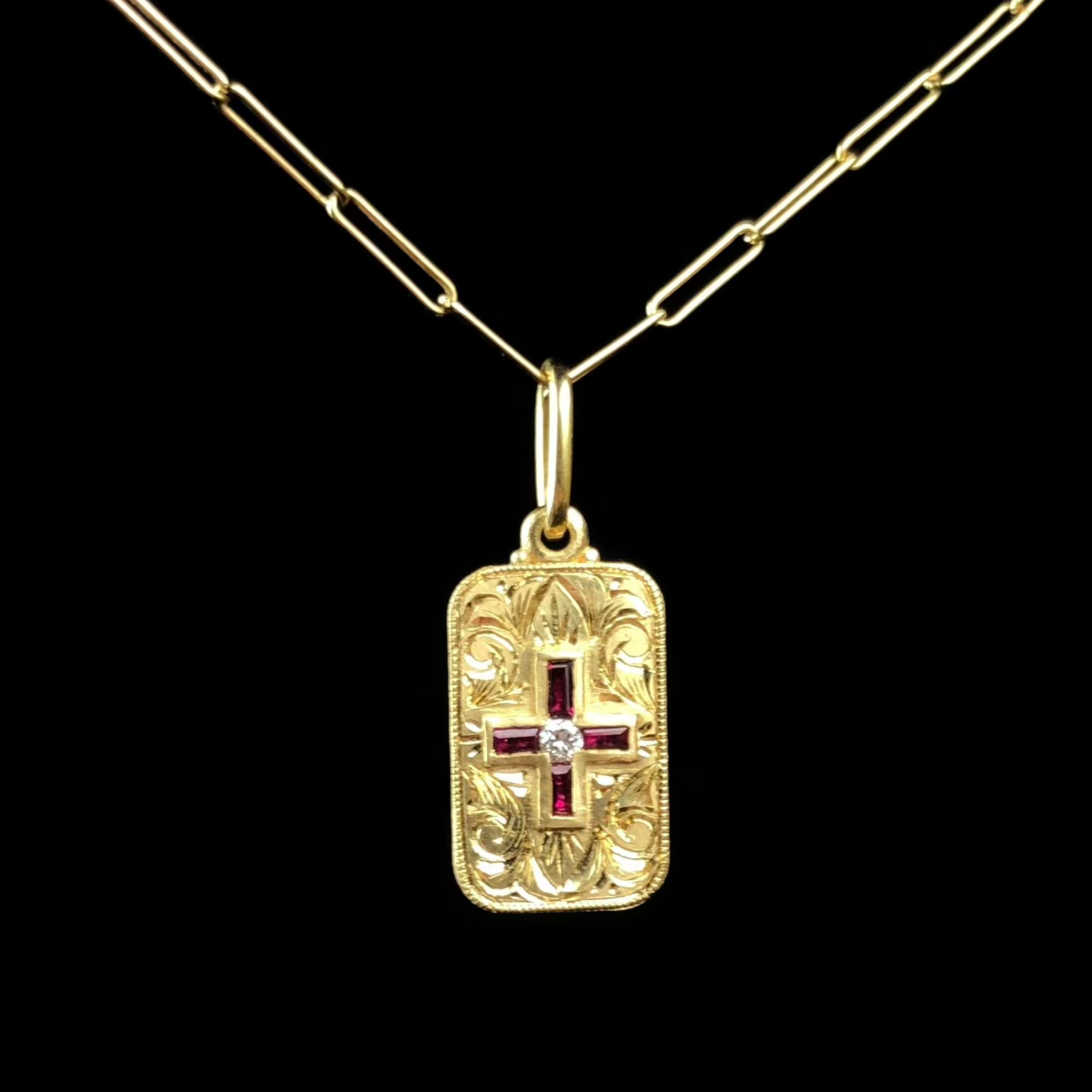 A rectangular gold pendant with red ruby stones set in the form of a cross in the center