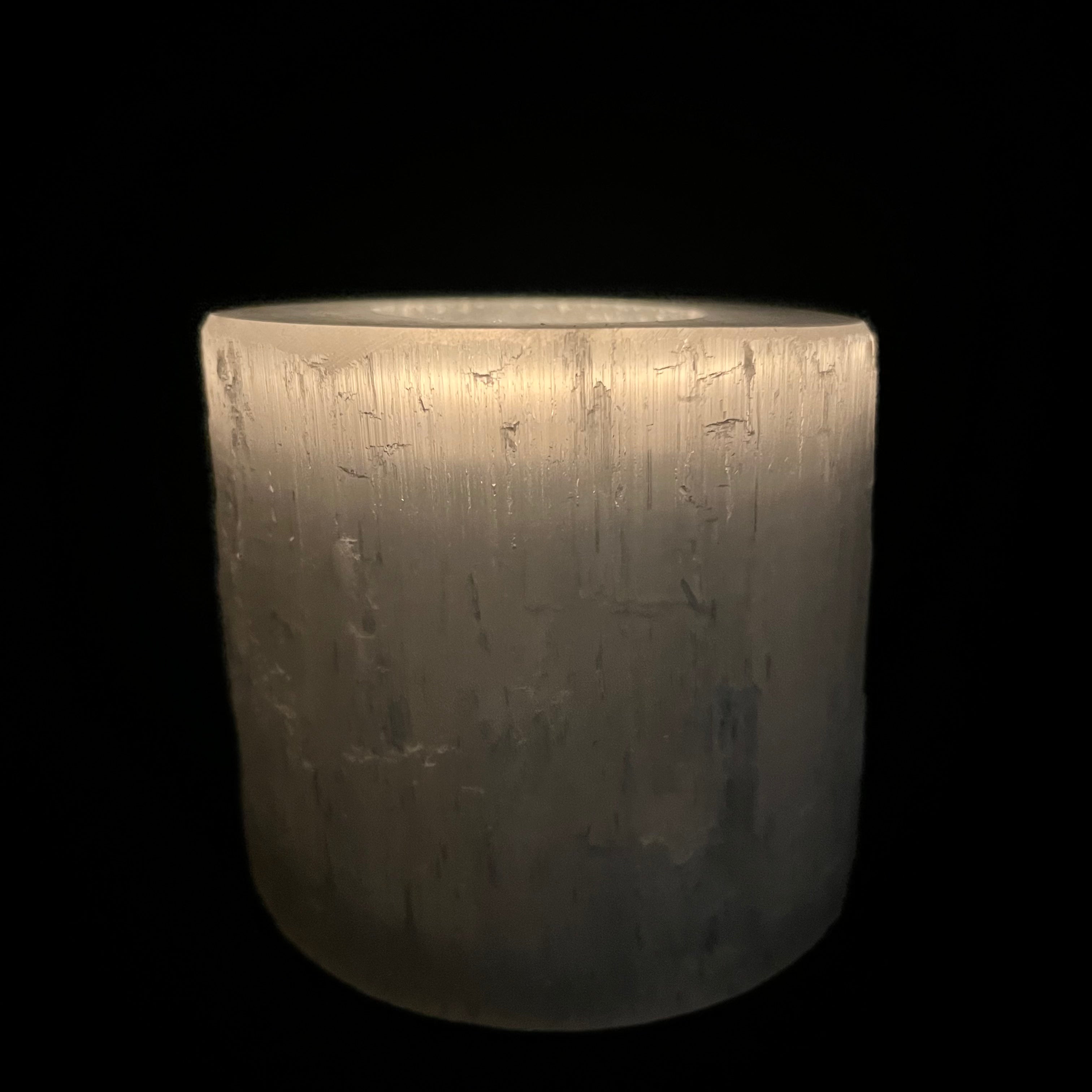 Front view of selenite candle holder lit in the dark